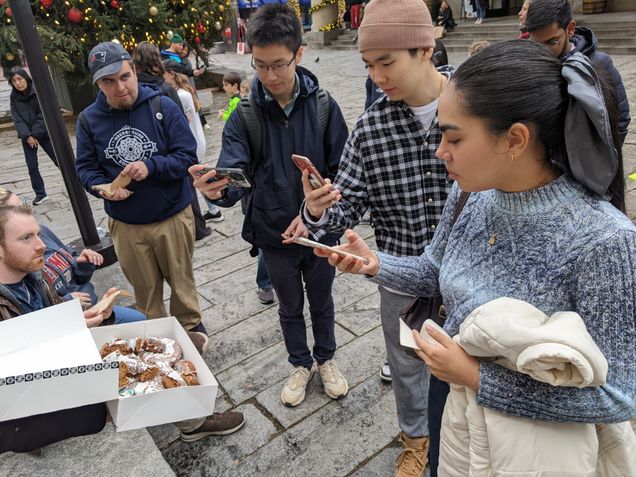 international students take photos of donuts in front of a decorated Christmas tree